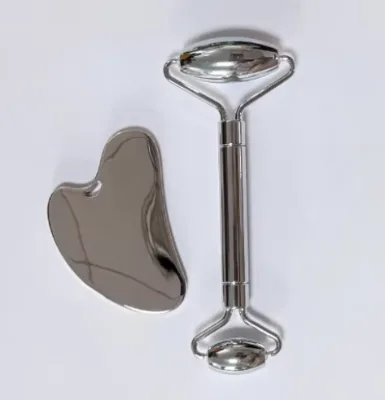 Set de masaje compuesto por rodillo facial y placa de gua sha fabricados en acero inoxidable